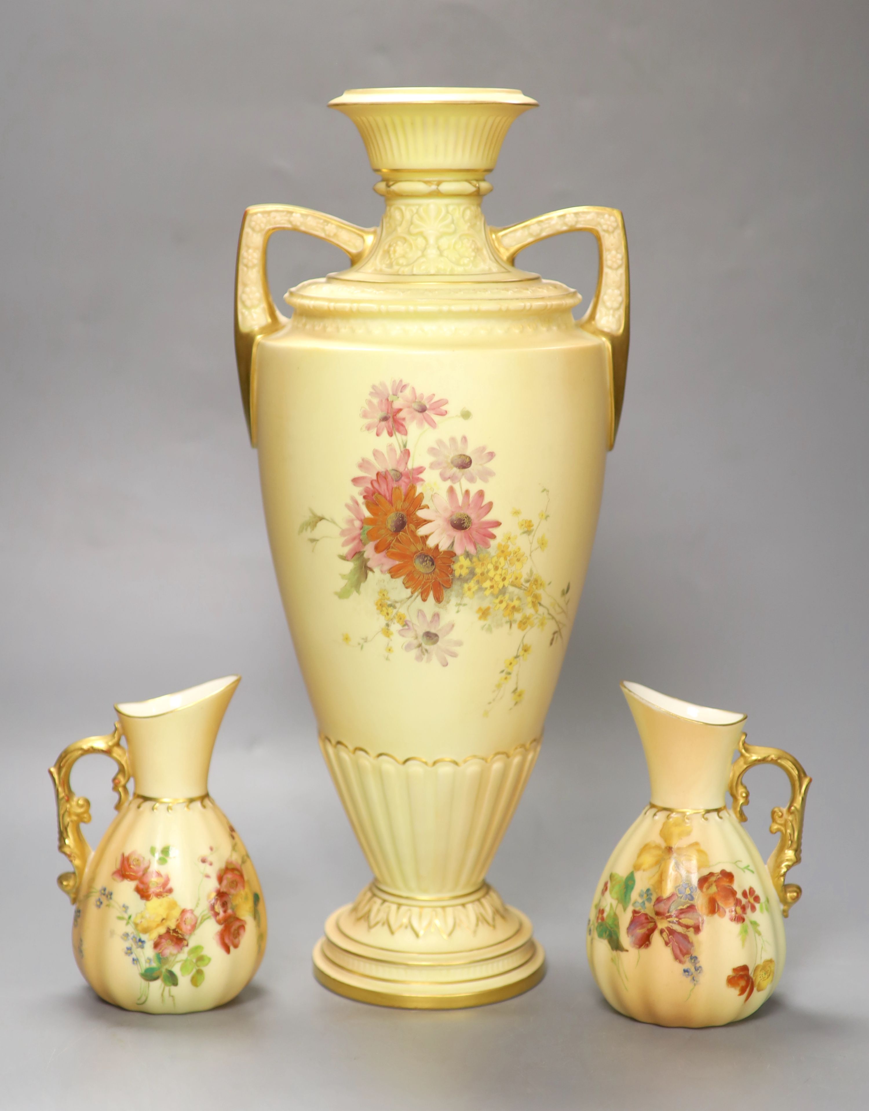 A Royal Worcester two-handled blush ivory vase, decorated with flowers, height 38cm, and a pair of similar jugs